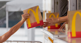 A McDonald's employee handing a bag of food to a customer